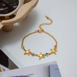 Macro detail of gold starfish bracelet with pink blue green and white gemstones