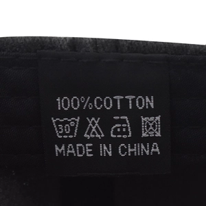 Detail of 100% cotton washing label with care instructions on a black baseball cap