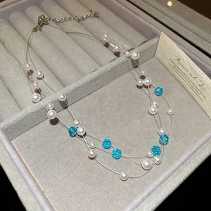 Detail of layered pearl and blue crystal necklace on a velvet jewelry box