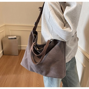 Side view of dark coffee canvas tote bag showing large capacity on a model in a minimal room