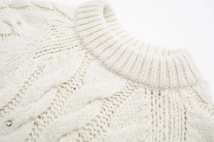 Nahaufnahme weißer Zopfstrickpullover mit geripptem Rundhalsausschnitt und Strassknöpfen