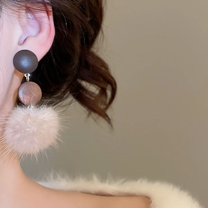 Detail of wooden and plush ball drop earring showing natural texture on female model