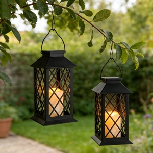 Close-up of two vintage solar lanterns with warm LED candles in a green garden setting