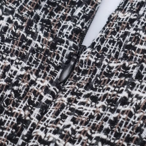 Gros plan sur un tissu tweed noir et blanc de haute qualité avec une fermeture éclair noire