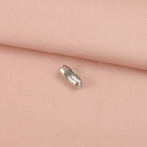 Close-up of silver stainless steel ball chain connector on pink fabric background