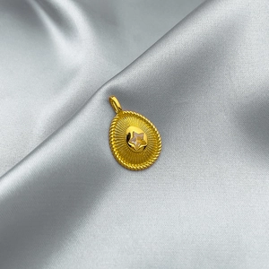 Golden oval pendant with star pattern on grey silk fabric, minimalist jewelry accessory
