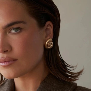 Fashionable matte gold seashell earrings worn by a model in a professional portrait style