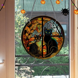 Detail of round acrylic suncatcher featuring two black cats against a moonlit autumn scene