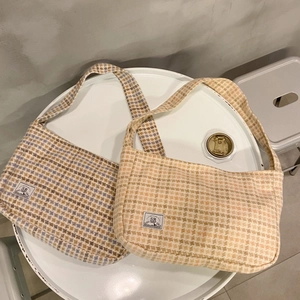 Close-up of wool plaid shoulder bags in blue and orange tweed with square logo tags
