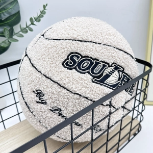 Detailed embroidery of Soule Play Dream text on a beige plush basketball pillow