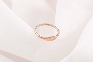 Macro shot of minimalist rose gold wavy band ring on elegant white pleated silk fabric