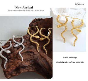 Macro detail of gold and silver snake earrings showing intricate engraved scale textures