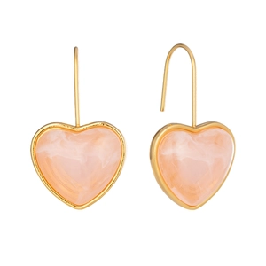 Détail de boucles d'oreilles cœur en résine rose marbrée avec crochets dorés