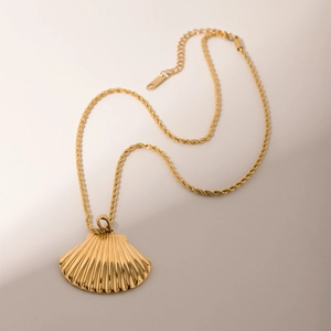 Detailed close-up of a gold shell pendant with a twisted chain and adjustable link