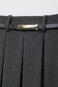 Detail view of dark grey pleated skirt featuring a black leather belt with a gold metal buckle