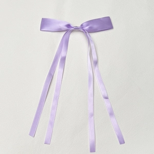 Detail of elegant purple satin hair bow with long streamers and smooth polyester ribbon