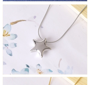 Macro shot of minimalist star pendant on a fine snake chain necklace in polished steel