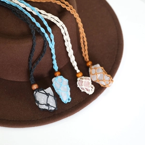 Detail of four colorful woven mesh necklaces with natural stones hanging on a brown felt hat