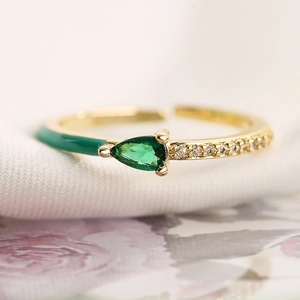 Macro detail of 18K gold ring with green drop gemstone and emerald enamel coating