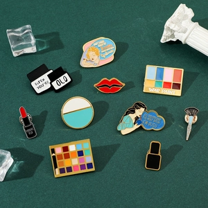 Flat lay of colorful enamel pins featuring lipstick, eye shadow, and makeup brush designs