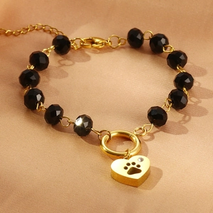 Detail of golden heart paw charm and black faceted beads on a sleek pet-themed bracelet