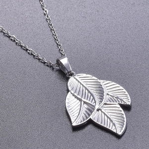Macro shot of silver stainless steel triple leaf pendant on textured grey surface