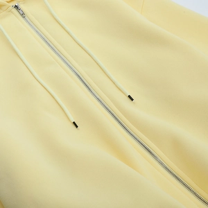Detailansicht des hellgelben Hoodie-Stoffs mit Metallreißverschluss und Kordelzug