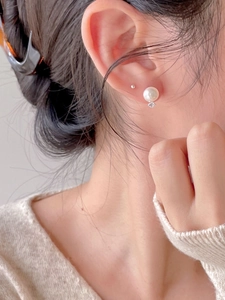 Close-up of 925 sterling silver pearl earrings with zircon detail on model ear