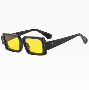 Detail view of square sunglasses with black frames, yellow lenses, and silver rivet accents