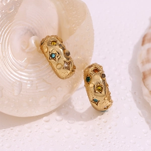 Macro shot of 18K gold earrings with colorful zircon stars and water drop effects