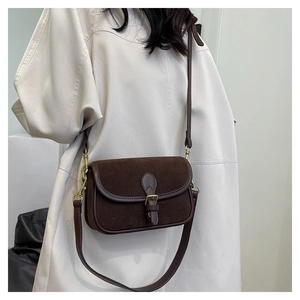 Detail of vintage dark brown crossbody bag with suede texture and gold buckle detail