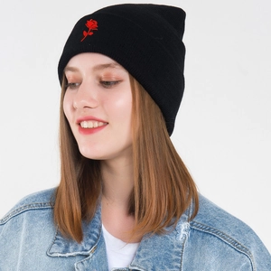 Women's black knitted beanie with red rose embroidery paired with casual denim jacket