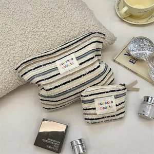 Macro detail of striped knitted makeup bags with a textured weave and designer labels