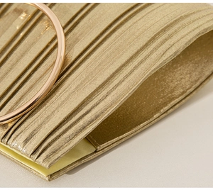 Detailed macro view of the gold pleated evening bag with its elegant metal ring handle