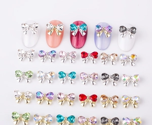 Macro view of bow-shaped alloy nail art charms with colorful rhinestones on white base