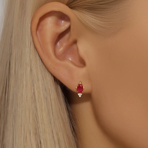 Macro view of gold-plated silver stud earring with ruby zircon and three-diamond accent