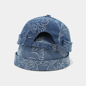 Detail of blue denim brimless docker hats with white leaf patterns and metal buckles