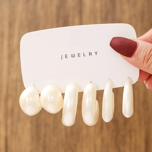 Detailed view of six assorted white faux pearl earrings displayed on a white jewelry card