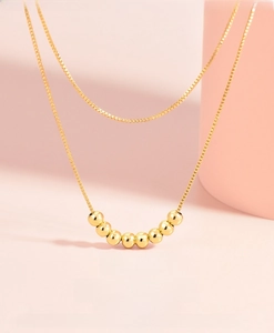 Detail of a 925 silver plated double-layer necklace with 8 polished gold round beads