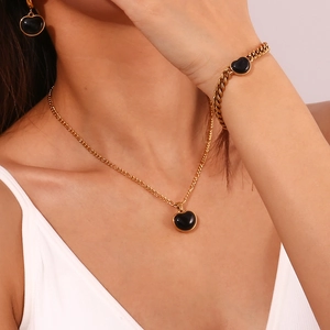 Model trägt vergoldetes Schmuckset mit schwarzen Onyx-Herzanhängern an Halsketten
