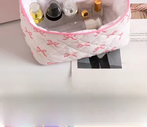 Close-up of white quilted makeup bag with pink bow print and internal storage space
