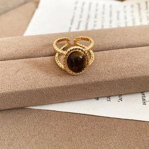 Close-up of 18k gold plated tiger eye ring with twist band on a velvet stand