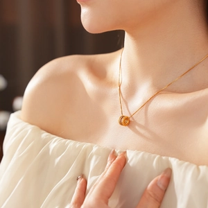 Close-up of gold-plated cylinder pendant necklace with red cubic zirconia on woman neckline