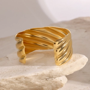 Close-up of gold 18k plated textured open cuff bracelet on a natural stone base