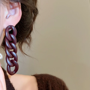 Detail of a model wearing large dark brown acrylic chain link drop earrings for women