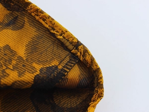 Detail of vintage gold jacquard lace fabric with intricate floral patterns and stitching