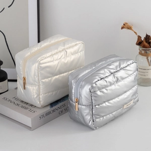 Close-up of quilted cosmetic bags in pearl white and silver with gold zippers