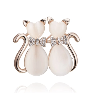 Detailed macro view of rose gold cat brooches featuring opal stones and rhinestone bows