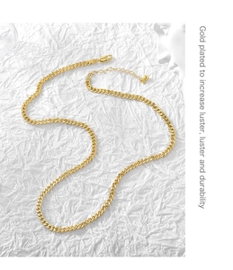 Detail of gold plated Cuban link necklace with lobster clasp on white textured background