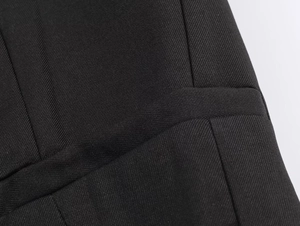 Dettaglio macro della trama in tessuto twill nero e delle cuciture della giacca corta